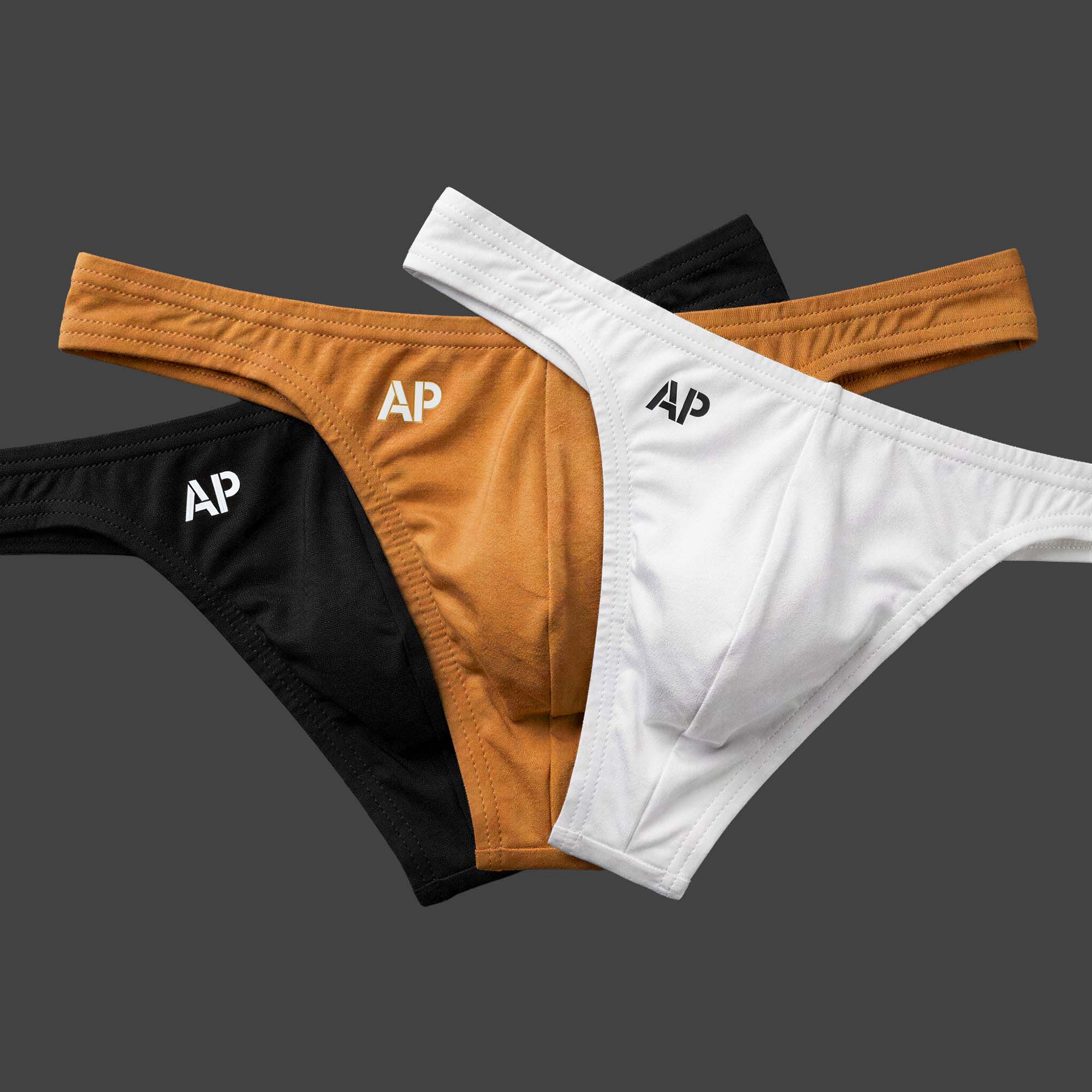 Pack: Pack x3 Tanga BASE TOTAL colores negro, camel y blanco. Vista conjunto con las tres piezas en disposición abanico. Alepadron.