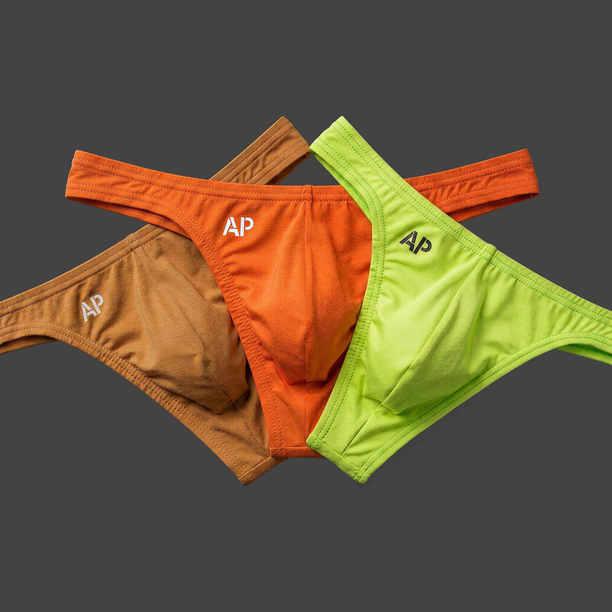 Pack: Pack x3 Tanga TERRACOTA colores camel, naranja y verde lima. Vista conjunto con las tres piezas en disposición abanico. Alepadron.